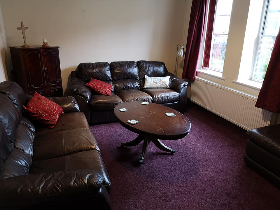 image of St Mark's room showing two comfortable sofas, a coffee table and a cabinet with a cross and candle